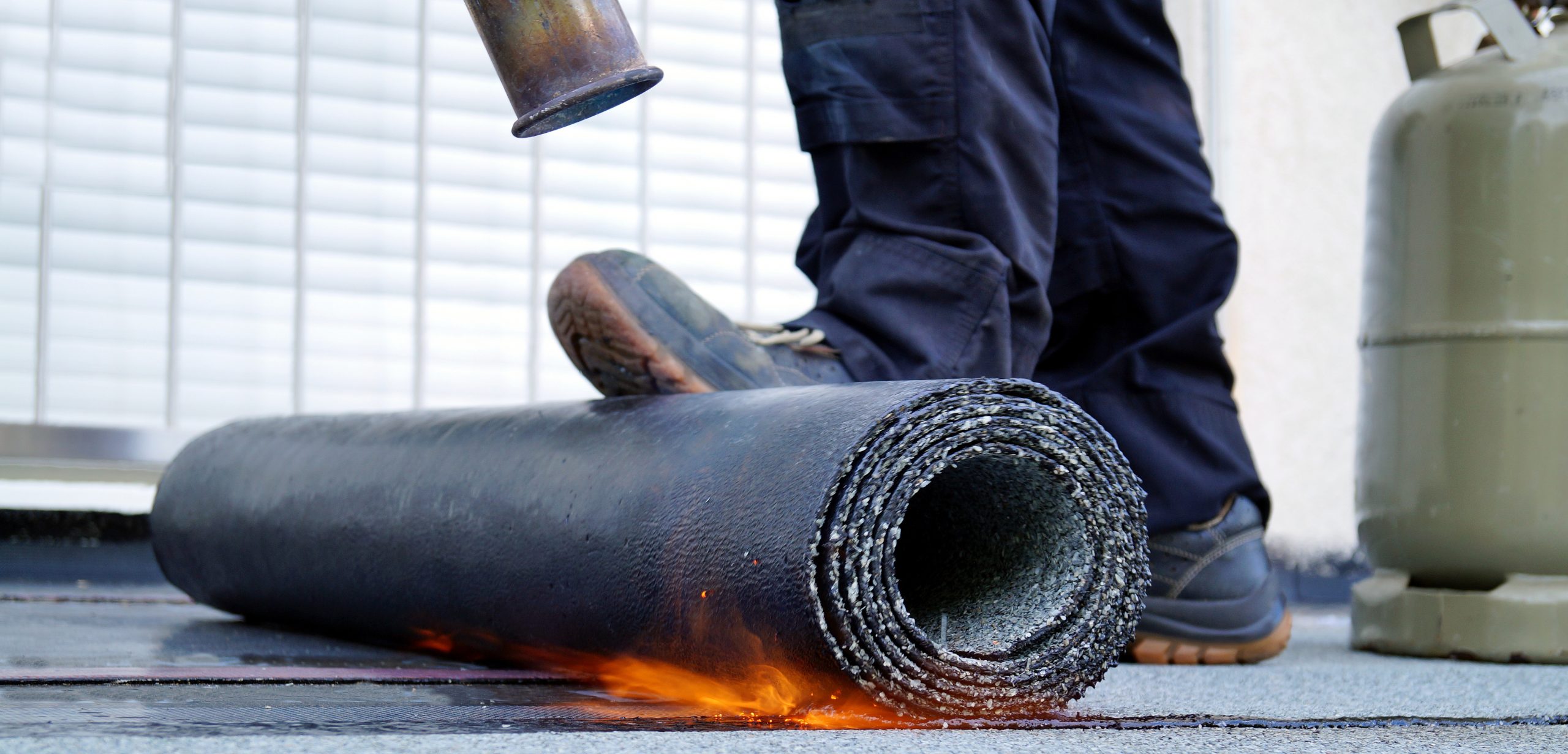 Heating and melting bitumen roofing felt. Flat roof installation with propane blowtorch during construction works with roofing felt. Roofing felt. Roofer working tool. Waterproofing, panoramic view